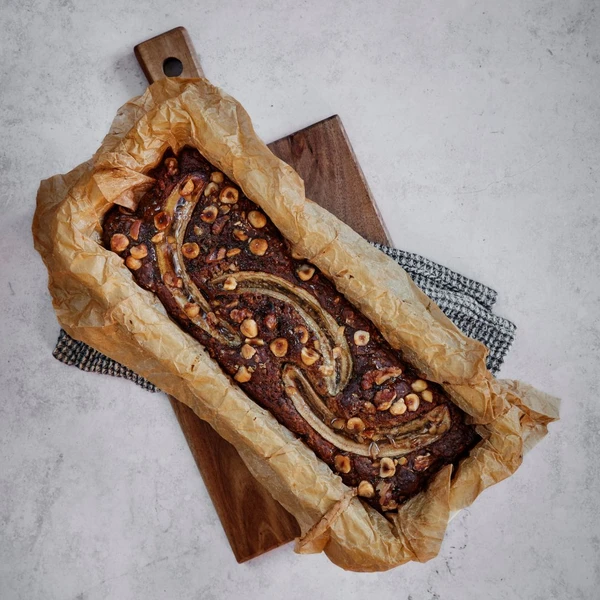 Homemade banana bread loaf on a wooden cutting board, made with Ankarsrum Assistent