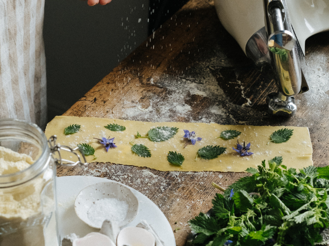 Ingredienser för pastadeg: mjöl, ägg och en mjölad arbetsyta.